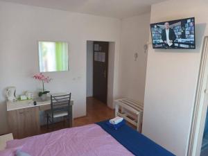 a bedroom with a bed and a tv on the wall at Guesthouse Villa Stanger in Lovran