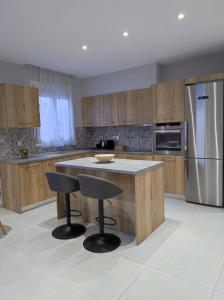 a kitchen with wooden cabinets and a island with two bar stools at Nostalgia Apartment in Archangelos