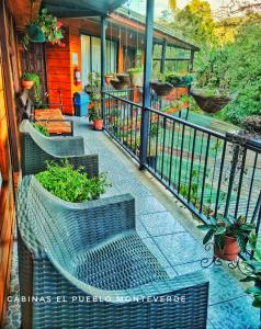 a balcony with two benches and a fence with plants at Cabinas El Pueblo B&B Monteverde in Monteverde Costa Rica