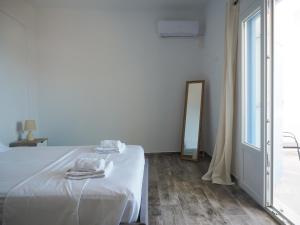 a white bedroom with a bed and a mirror at Papillon in Pera Gyalos