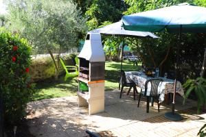 a grill in a garden with a table and an umbrella at O Quadradinho in Tavira