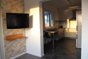 cocina con TV de pantalla plana en la pared en A L'orée des vignes, superbe logement de 80 m2, en Wangen