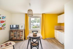 a kitchen with yellow walls and a table and chairs at Comme un Poisson dans l'Eau - Côté Mer -Belle vue mer in Saint-Benoît-des-Ondes