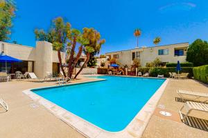 a swimming pool with chairs and a building at Tennis on El Paseo at Sandroc Permit# STR2023-0030 in Palm Desert