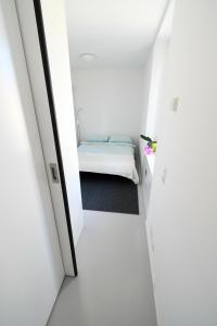 una piccola camera bianca con un letto. di Splendido appartamento a due passi da Locarno a Tenero-Contra