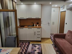 cocina con armarios blancos y sala de estar con sofá en Lux Apartmani Bajova, en Cetinje