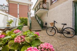 rower zaparkowany obok budynku z różowymi kwiatami w obiekcie Villa Cecilia - Casa marinera con piscina y jardín w mieście Colindres