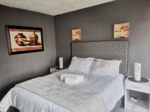 a bedroom with a bed with white sheets and a painting at The Calm Views Holiday Home in Hazyview