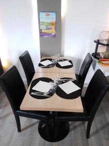 une table en bois entourée de chaises noires dans l'établissement Logis Drom'sud Hotel, à Donzère