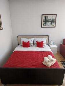 een bed met rode kussens en 2 handdoeken erop bij Apartman Sabah in Novi Pazar