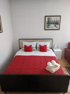 a bed with red pillows and two towels on it at Apartman Sabah in Novi Pazar