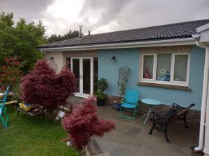 een blauw huis met een patio met stoelen en een tafel bij No 9 Manor Way in Carmarthen