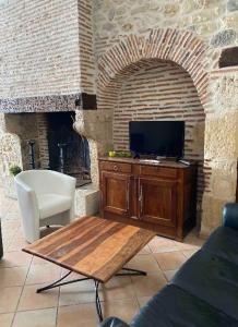 een woonkamer met een tv en een open haard bij Maison de casteljaloux 9 personnes in Casteljaloux