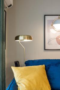 a blue couch with a yellow pillow next to a lamp at D&D apartments 4 in Palanga +27 photos