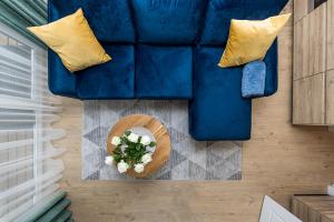 a blue couch with yellow pillows and a table with flowers at D&D apartments 4 in Palanga