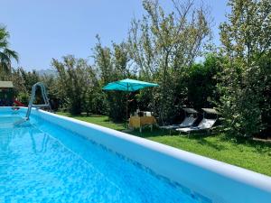 a swimming pool with a blue umbrella and chairs at Villa Valentino Pompeji in Pompei