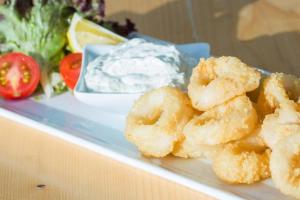 a plate of food with onion rings and a bowl of dip at Teos Ormanci Tatil Koyu in Seferihisar