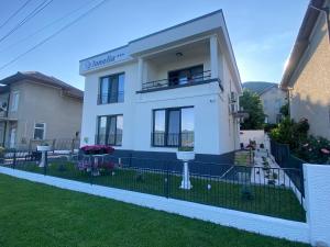 une maison blanche avec une clôture devant elle dans l'établissement Pensiunea Ionelia, à Orşova
