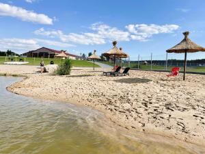 a beach with some chairs and umbrellas and water at Hotel Sebory in Przasnysz +47 photos
