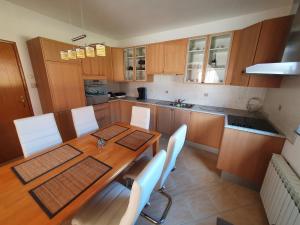 cocina con mesa de madera y sillas blancas en House Antea en Lučko