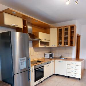 a kitchen with a stainless steel refrigerator and white cabinets at Apartment Mladinić Muse in Pučišća