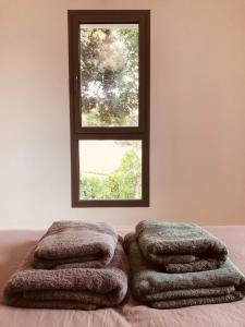 a bedroom with a window and two towels on a bed at Villa- Vaux sur mer -200 m plage Nauzan - Piscine in Vaux-sur-Mer