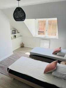 drie bedden in een kamer met witte muren bij Appartement Cosy en coeur de vieille ville in Boulogne-sur-Mer