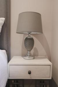 una lámpara en una mesita de noche junto a una cama en The Gardens Room en Upton