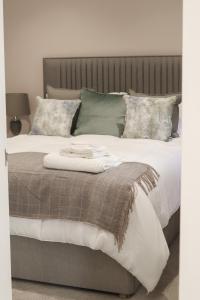 ein Bett mit einer braunen und weißen Decke und Kissen in der Unterkunft The Gardens Room in Upton