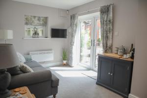 a living room with a couch and a sliding glass door at The Gardens Room in Upton