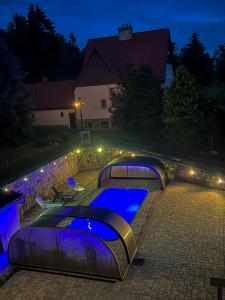 a pool with four canopy beds at night at Resort LUFT Sněžník in Sněžnik