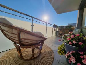 a wooden rocking chair sitting on a balcony with flowers at Apartament Madlen Art in Olecko