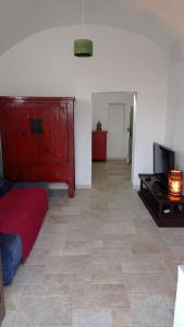 een woonkamer met een rood bed en een televisie bij LA CASA DI BEL in Monopoli