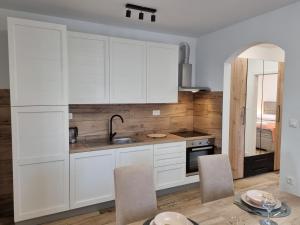 a kitchen with white cabinets and a table with chairs at Apartman Lovre in Zadar