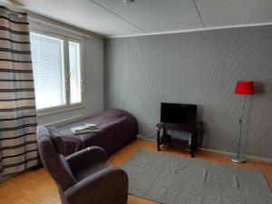 a living room with a bed and a chair and a television at Mikko's house in Pori