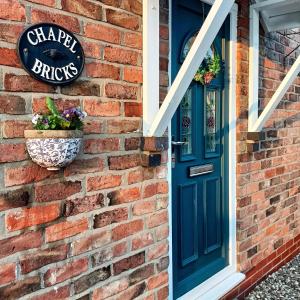 uma casa de tijolos com uma porta azul e uma janela em Chapel Bricks-dog friendly cottage near the coast em Withernwick