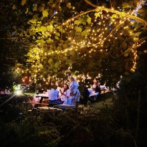Dworek sw.Antoniego في Sławutowo: مجموعة من الناس يجلسون على الطاولات تحت شجرة مع أضواء