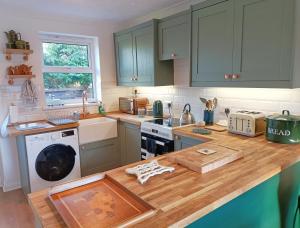 cocina con armarios verdes y encimera de madera en Chapel Bricks-dog friendly cottage near the coast en Withernwick