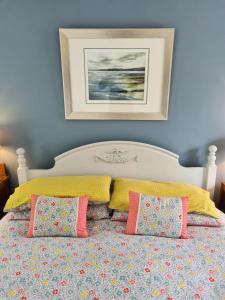 1 cama con almohadas coloridas y una foto en la pared en Chapel Bricks-dog friendly cottage near the coast en Withernwick