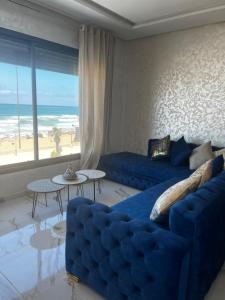 sala de estar con sofá azul y vistas a la playa en Golden Beach Elegance Sea View & Serenity, en Kenitra