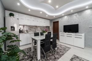 una cucina con mobili bianchi e un tavolo con sedie di City Apartments - a brand new luxury & comfy 2 a Asenovgrad