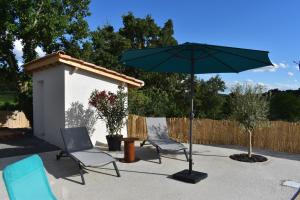 a patio with two chairs and an umbrella at Gite des Clapas Flora, villa avec piscine privée in Balazuc