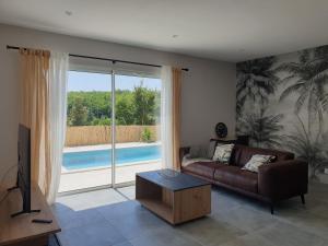 a living room with a couch and a view of a pool at Gite des Clapas Flora, villa avec piscine privée in Balazuc
