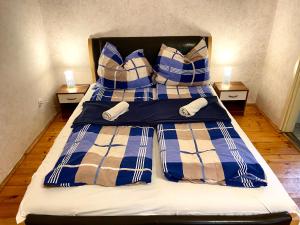 a bed with blue and white plaid sheets and pillows at Goldschmiedt Vendégház in Pálköve