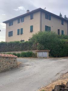 a large white building with green shuttered windows at Antica Casa Prile in Castiglione della Pescaia