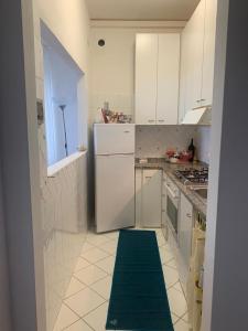 a white kitchen with a green rug on the floor at Antica Casa Prile in Castiglione della Pescaia +6 photos