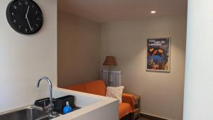 a kitchen with an orange couch and a clock on the wall at StudiÒ Lalex28 in Aosta