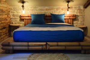 a bedroom with a blue bed with a stone wall at Domaine Moulin de Quincenat Gîte Moulin au Bois Dormant in Champagnat