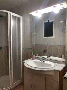 a bathroom with a sink and a shower and a television at Playa Vinaroz in Vinarós