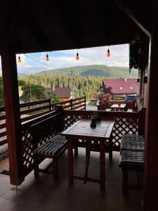 a wooden table and benches on a balcony with a view at Villa Montana Borsec - Vedere Munte in Borsec